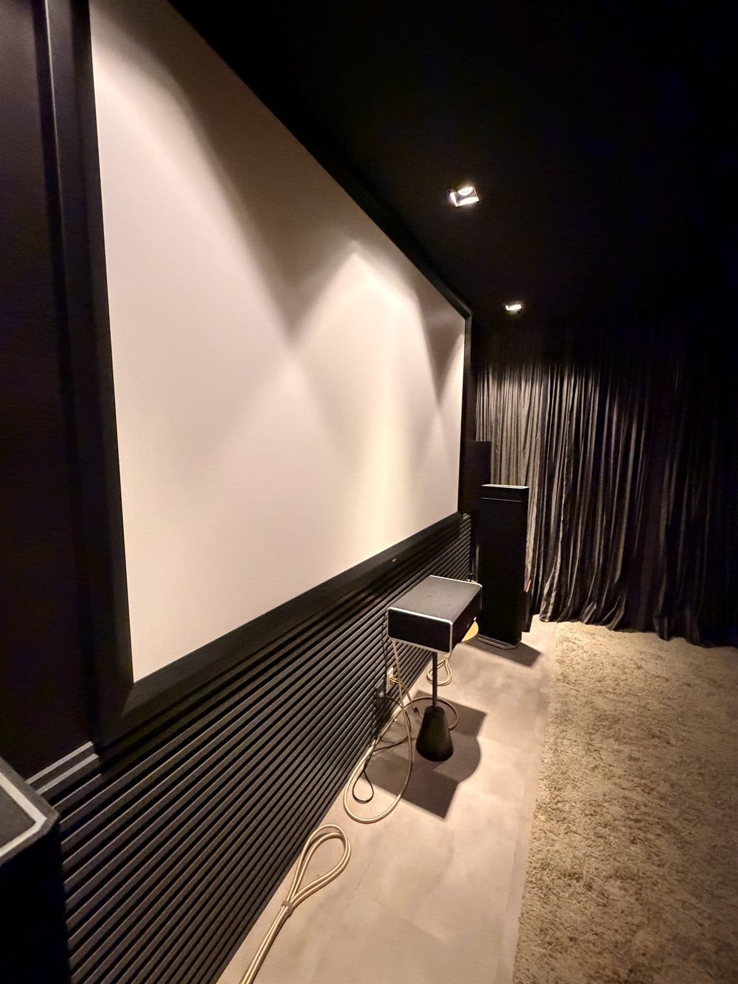 Sala de home theater residencial com projetor de alta definição e tela grande, ambiente escurecido com poltronas de lounge