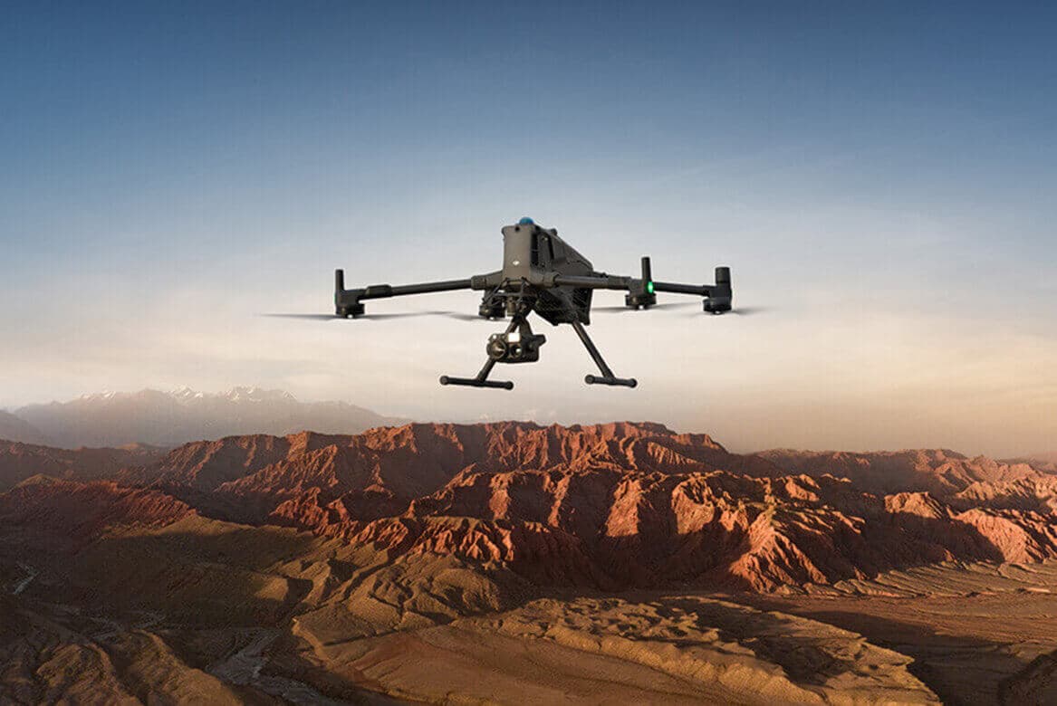 Drone profissional DJI Enterprise em voo sobre terreno acidentado ao entardecer