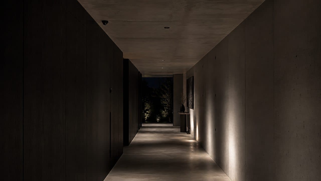 Corredor residencial minimalista à noite com câmera de segurança discreta no teto, ambiente ainda escuro